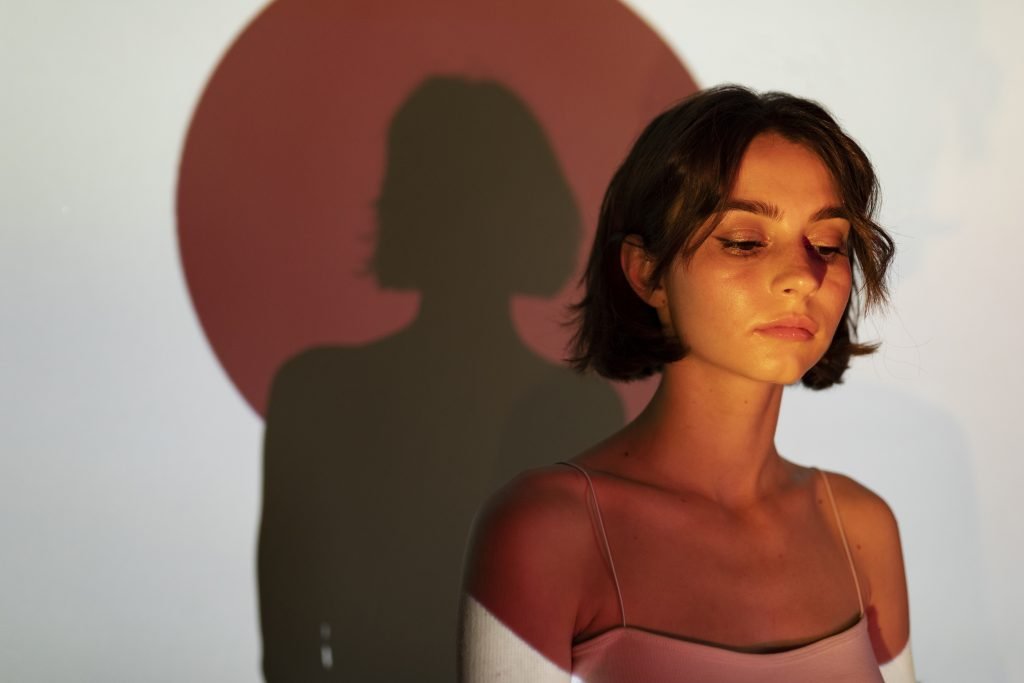 Mujer joven en sombra proyectada, con expresión seria, simbolizando introspección y relaciones narcisistas – Ana Serrano Psicóloga.